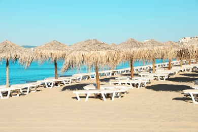Photo of Straw umbrellas and sunbeds on sandy beach