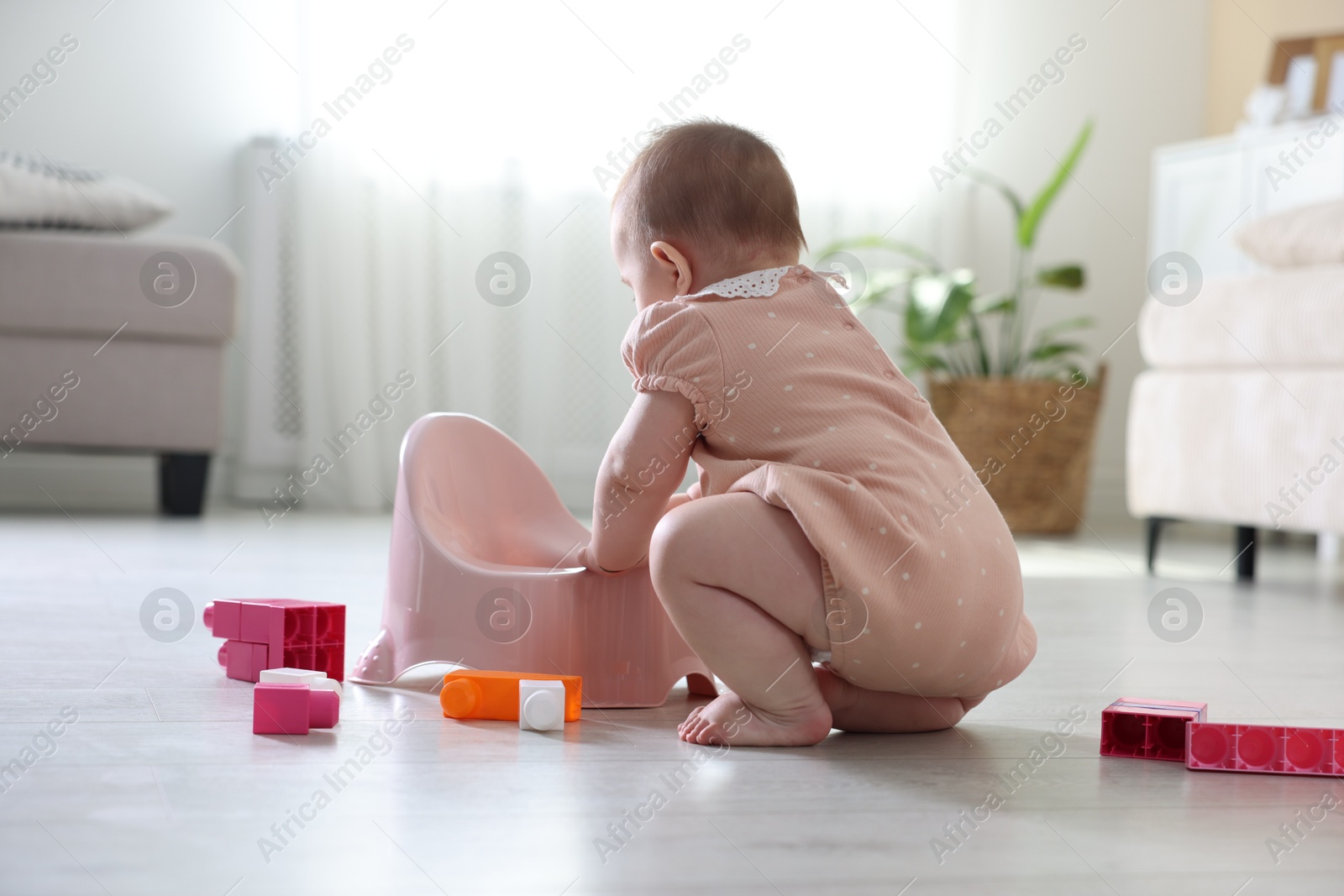 Cute little baby with potty and toys on floor at home Photo of Cute little baby with potty and toys on floor at home