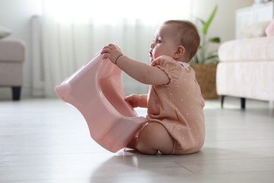 Photo of Cute little baby with potty on floor at home