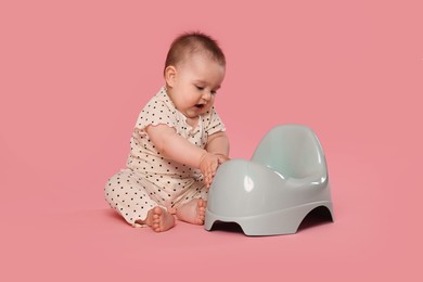 Photo of Cute little baby sitting near potty on pink background