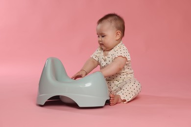 Photo of Cute little baby sitting near potty on pink background