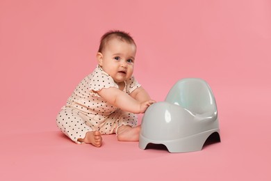Photo of Cute little baby sitting near potty on pink background