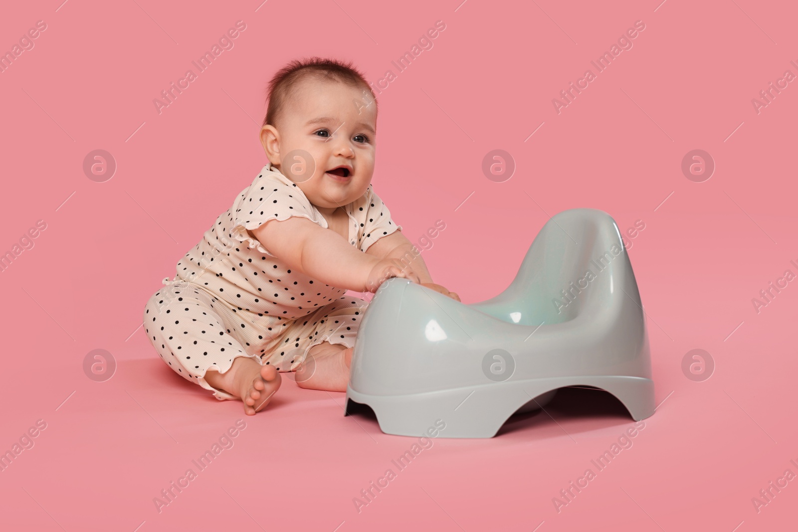 Photo of Cute little baby sitting near potty on pink background