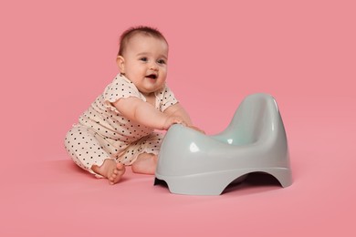 Photo of Cute little baby sitting near potty on pink background