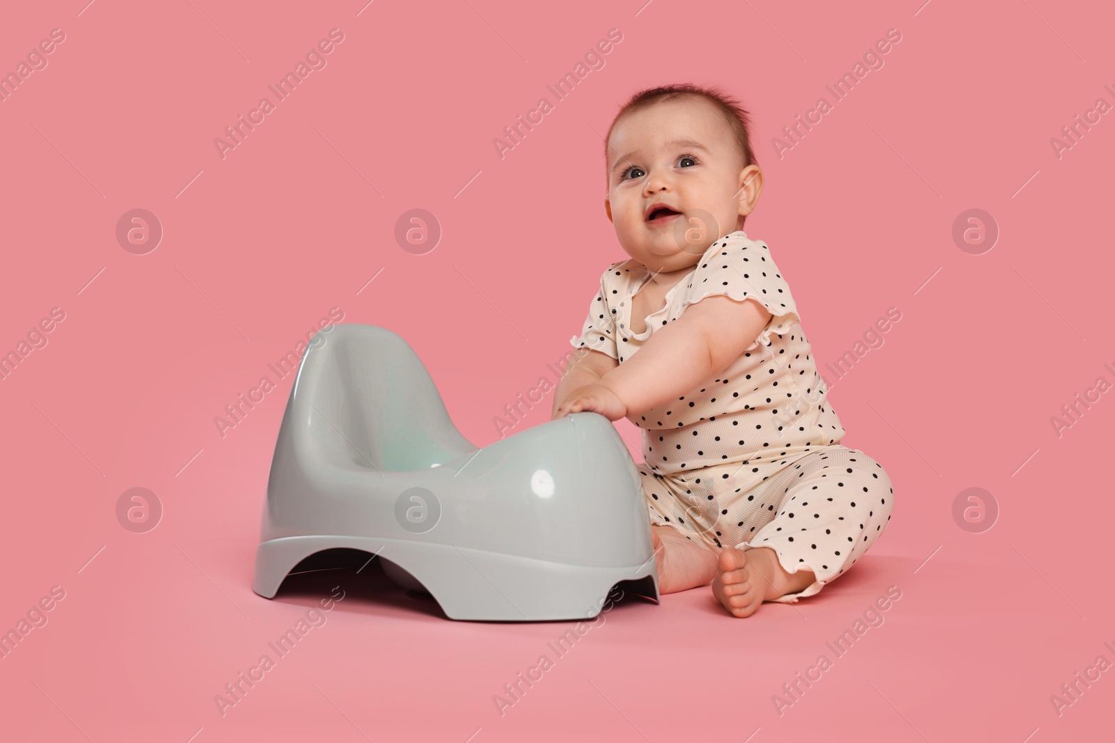 Cute little baby sitting near potty on pink background Photo of Cute little baby sitting near potty on pink background