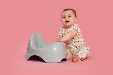 Photo of Cute little baby sitting near potty on pink background