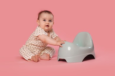 Photo of Cute little baby sitting near potty on pink background