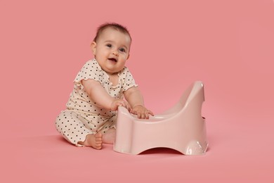 Photo of Cute little baby sitting near potty on pink background