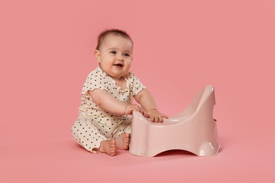 Photo of Cute little baby sitting near potty on pink background