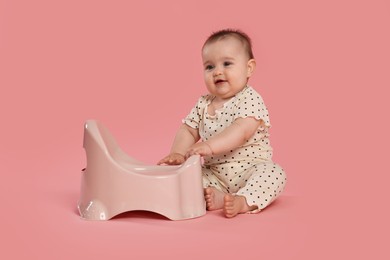 Photo of Cute little baby sitting near potty on pink background