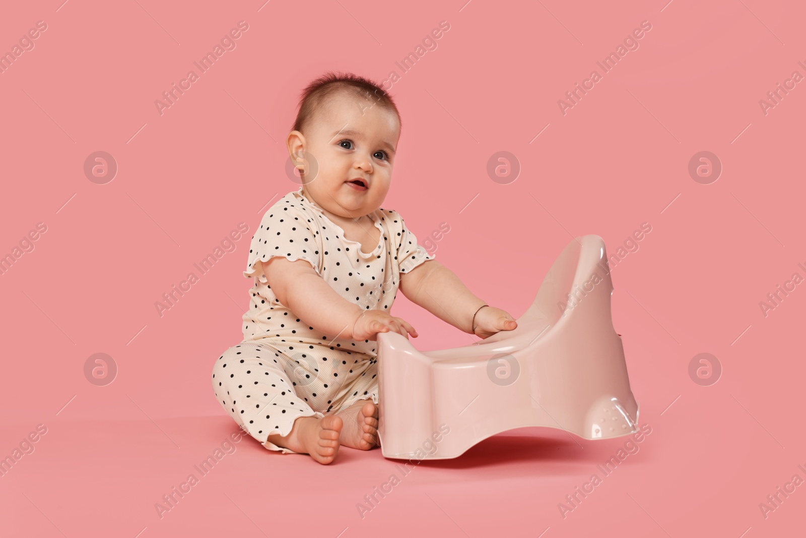Cute little baby sitting near potty on pink background Photo of Cute little baby sitting near potty on pink background