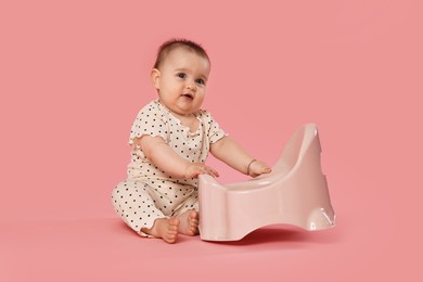 Photo of Cute little baby sitting near potty on pink background