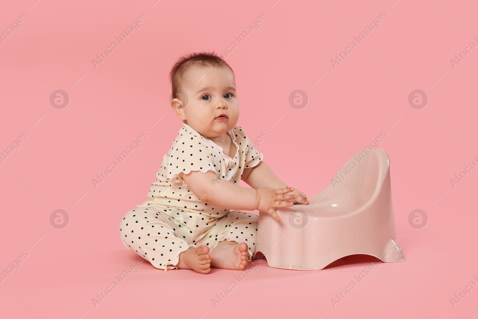 Cute little baby sitting near potty on pink background Photo of Cute little baby sitting near potty on pink background