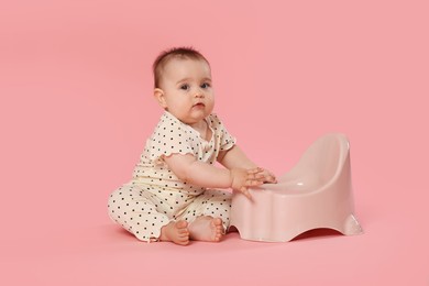 Photo of Cute little baby sitting near potty on pink background