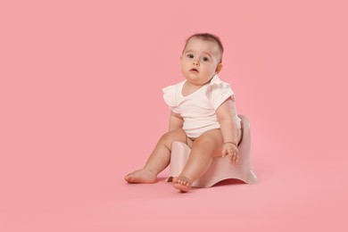 Photo of Cute little baby sitting on potty against pink background, space for text