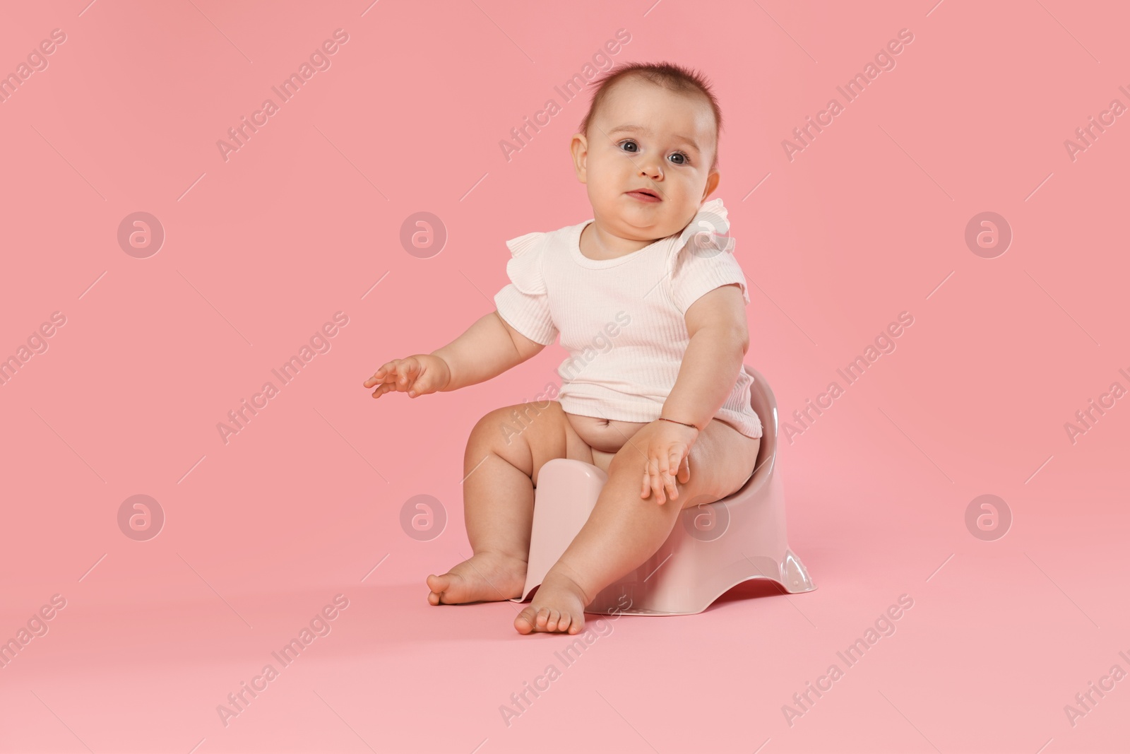 Cute little baby sitting on potty against pink background Photo of Cute little baby sitting on potty against pink background