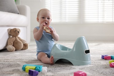 Photo of Cute little baby with teether sitting near potty at home