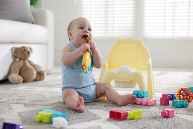 Photo of Cute little baby with toy sitting near potty at home