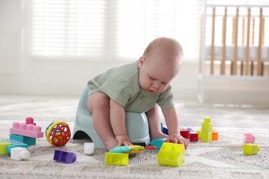 Photo of Cute little baby sitting on potty and toys at home