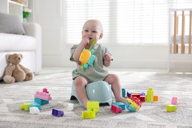 Photo of Cute little baby with toy sitting on potty at home