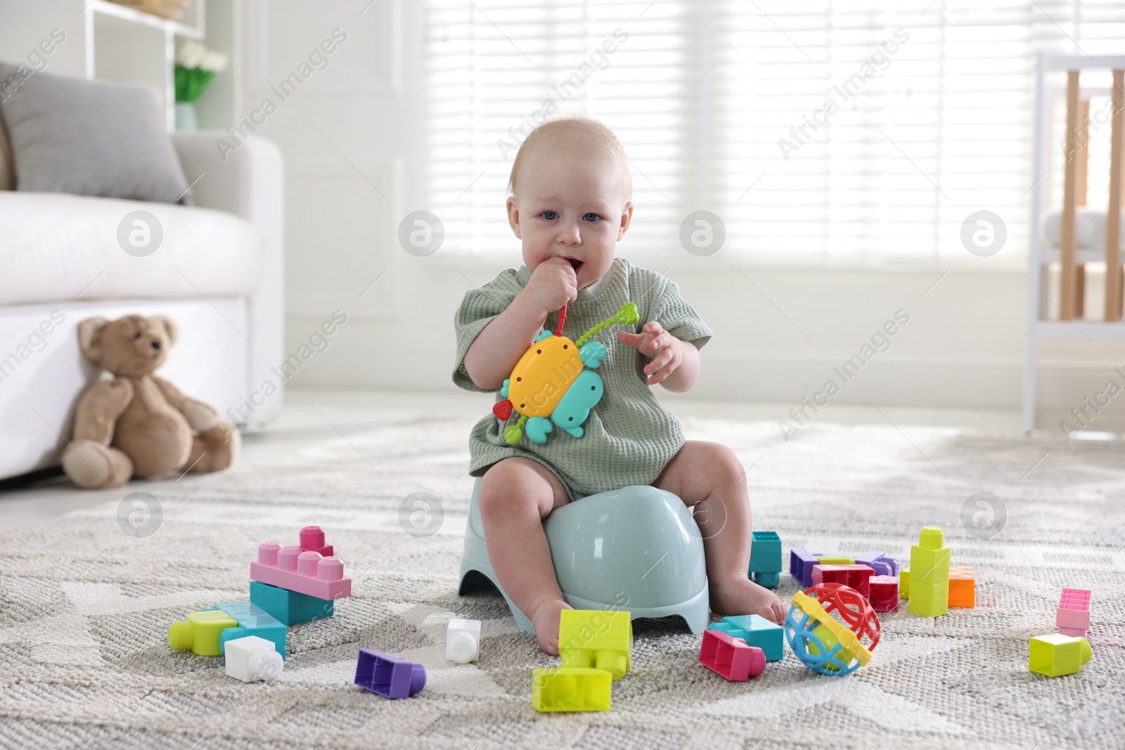 Photo of Cute little baby with toy sitting on potty at home