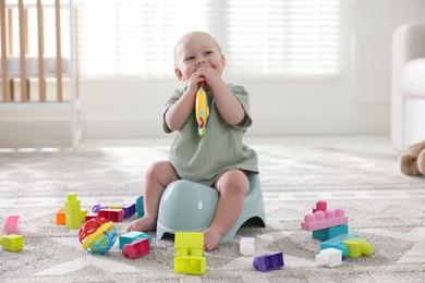 Photo of Cute little baby with toy sitting on potty at home
