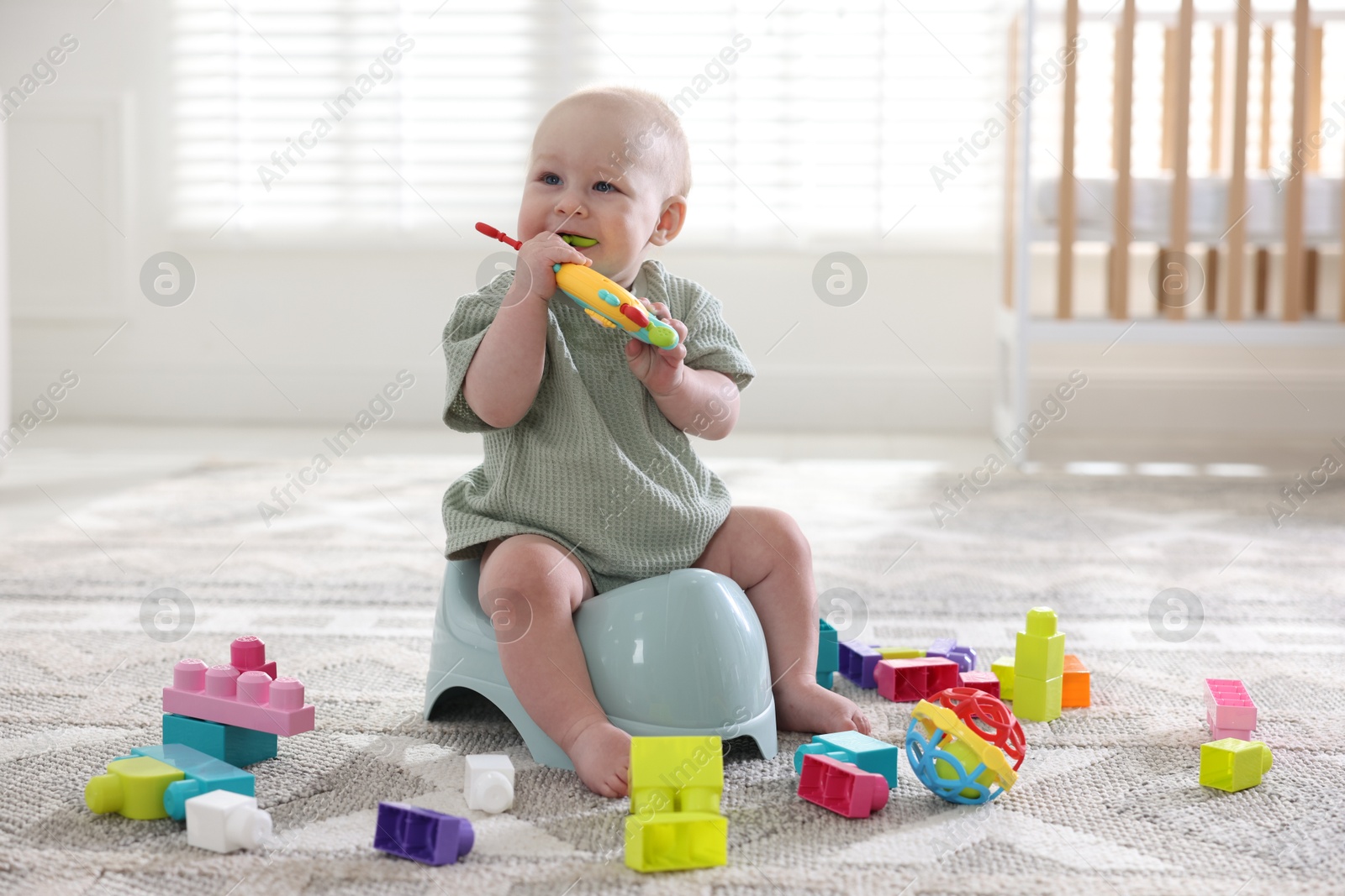 Cute little baby with toy sitting on potty at home Photo of Cute little baby with toy sitting on potty at home