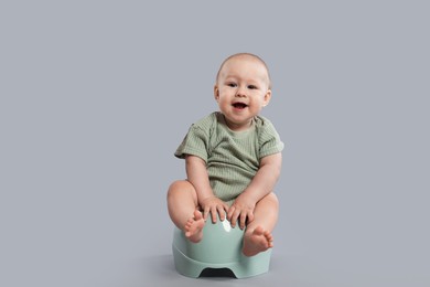 Photo of Cute little baby sitting on potty against light grey background
