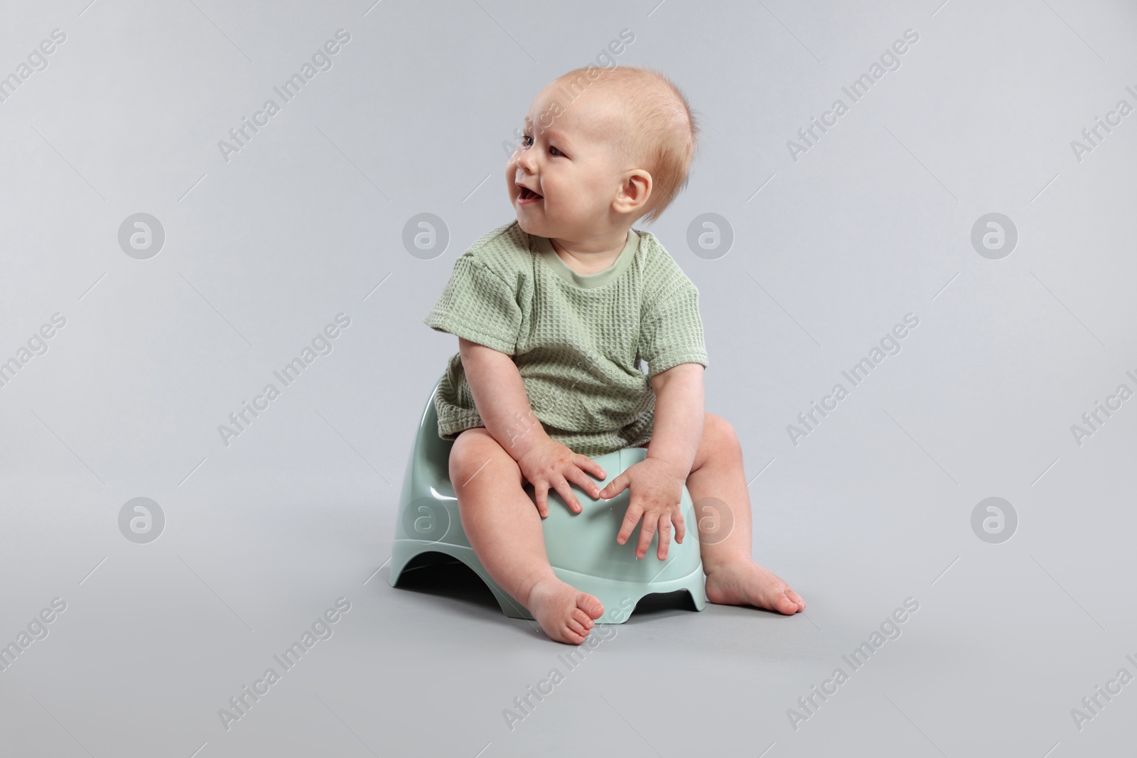 Cute little baby sitting on potty against light grey background Photo of Cute little baby sitting on potty against light grey background