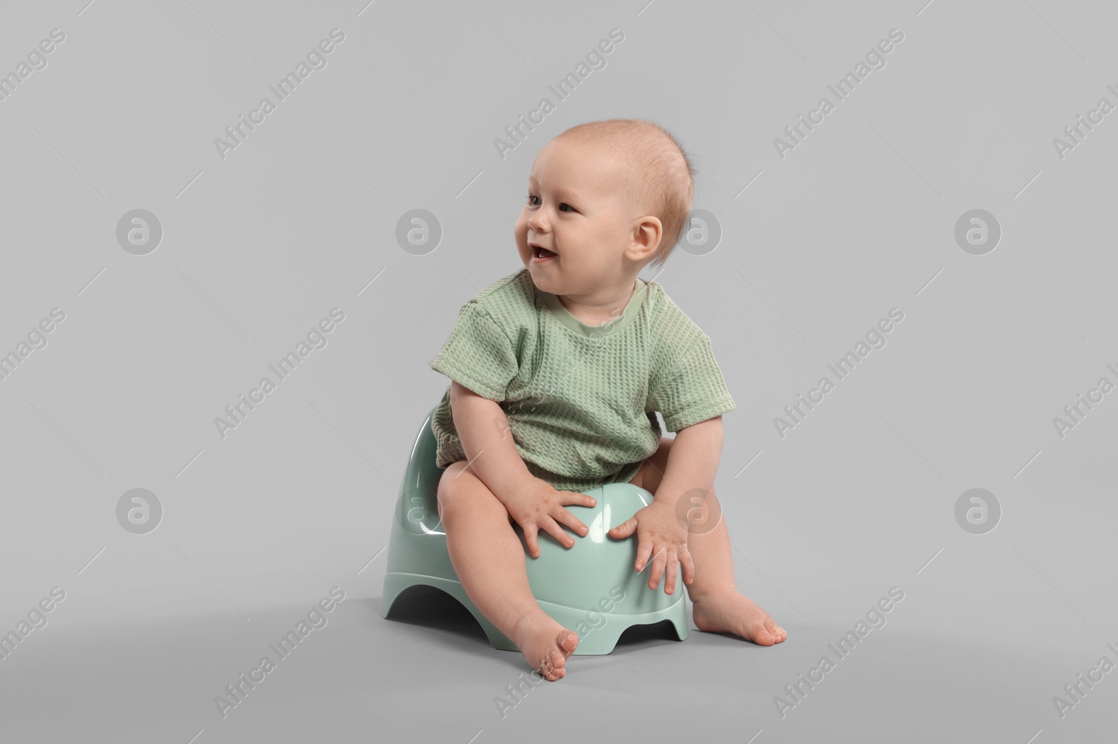 Cute little baby sitting on potty against light grey background Photo of Cute little baby sitting on potty against light grey background