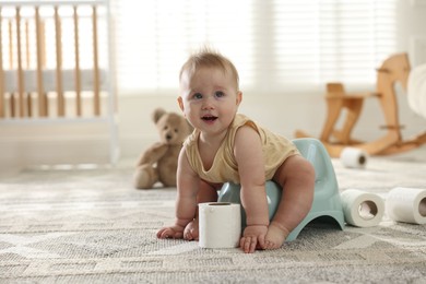 Photo of Cute little baby sitting on potty and toilet paper at home, space for text