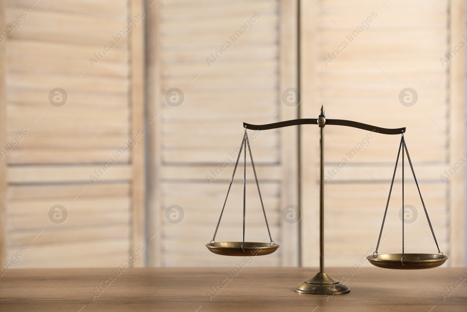 Photo of Golden scales of justice on wooden table, space for text