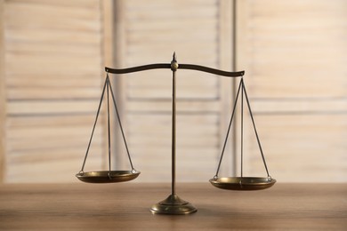 Photo of Golden scales of justice on wooden table