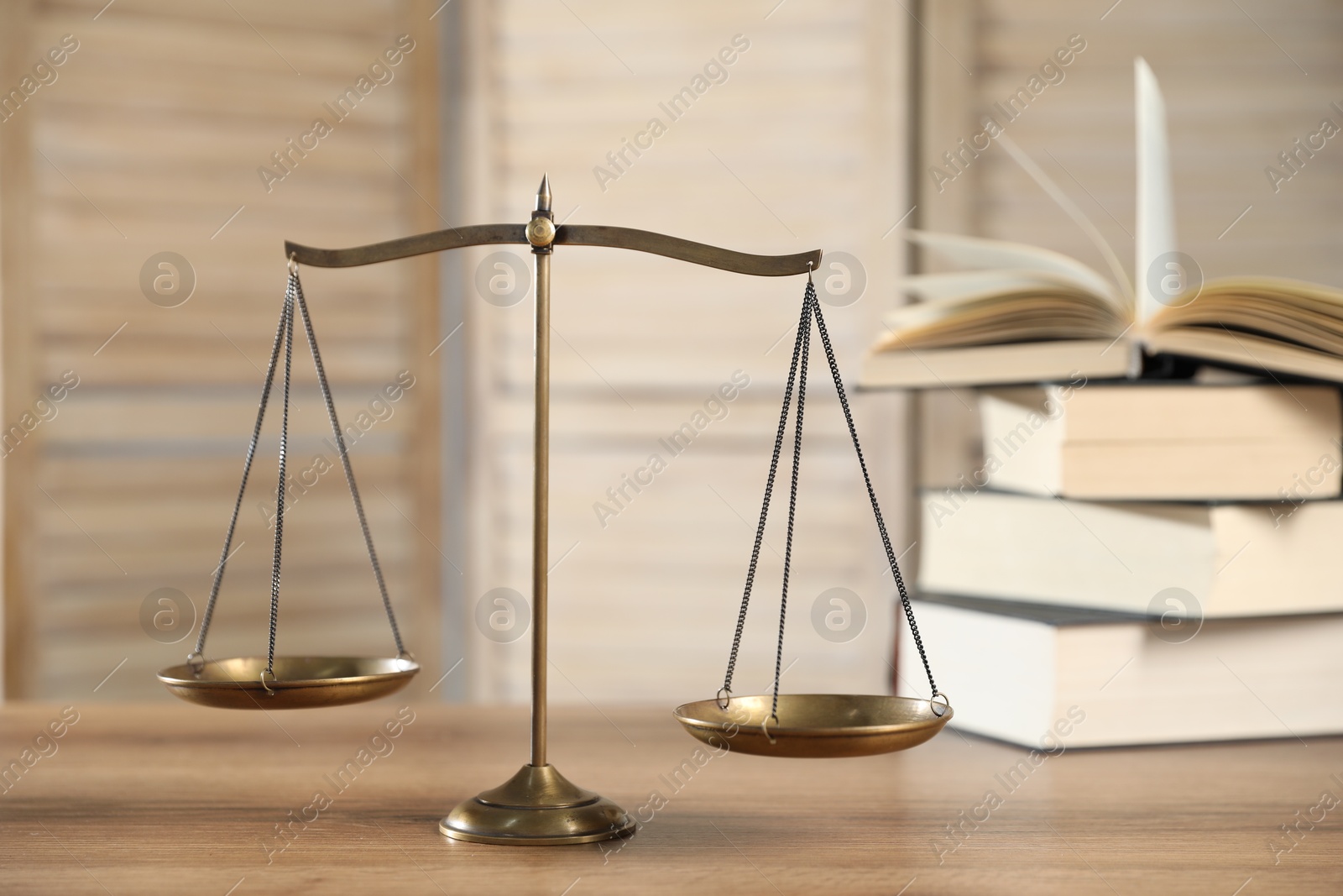 Golden scales of justice and books on wooden table Photo of Golden scales of justice and books on wooden table
