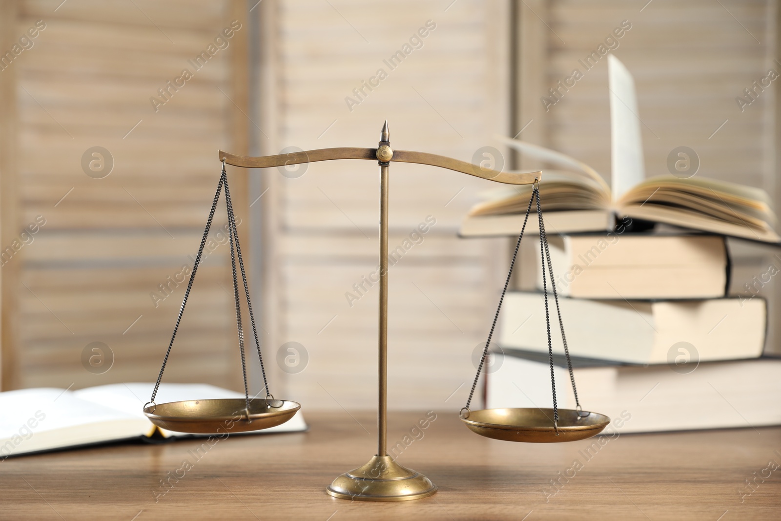 Photo of Golden scales of justice and books on wooden table
