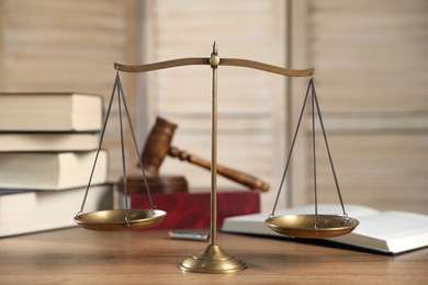 Photo of Golden scales of justice, gavel and books on wooden table