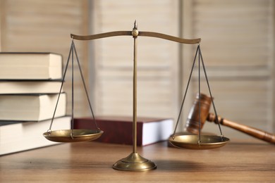 Photo of Golden scales of justice, gavel and books on wooden table