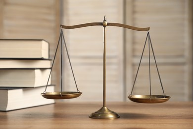 Photo of Golden scales of justice and books on wooden table