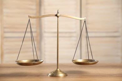 Photo of Golden scales of justice on wooden table