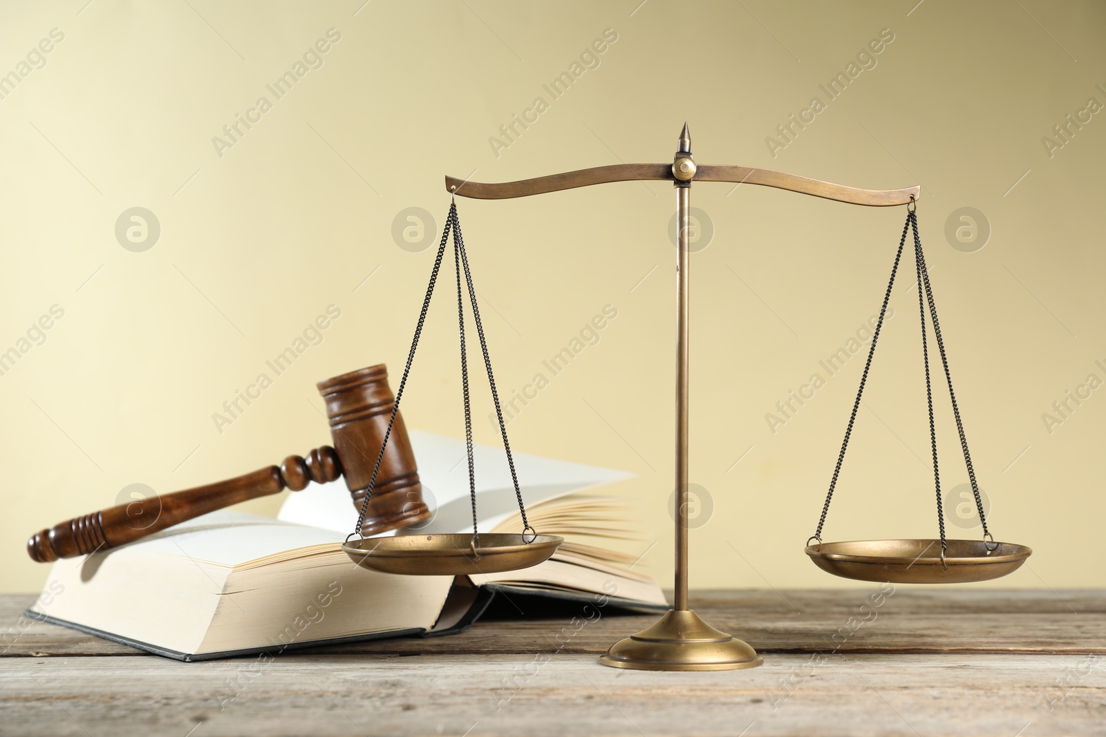 Golden scales of justice, gavel and book on wooden table against beige background Photo of Golden scales of justice, gavel and book on wooden table against beige background