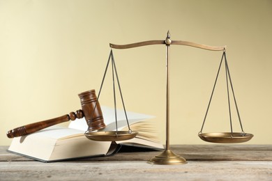 Photo of Golden scales of justice, gavel and book on wooden table against beige background