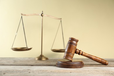Photo of Golden scales of justice and gavel on wooden table against beige background, selective focus