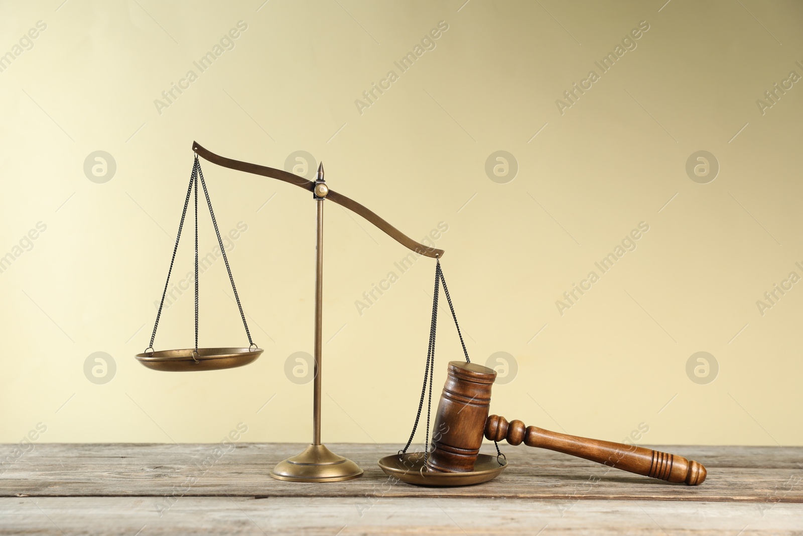 Photo of Golden scales of justice and gavel on wooden table against beige background