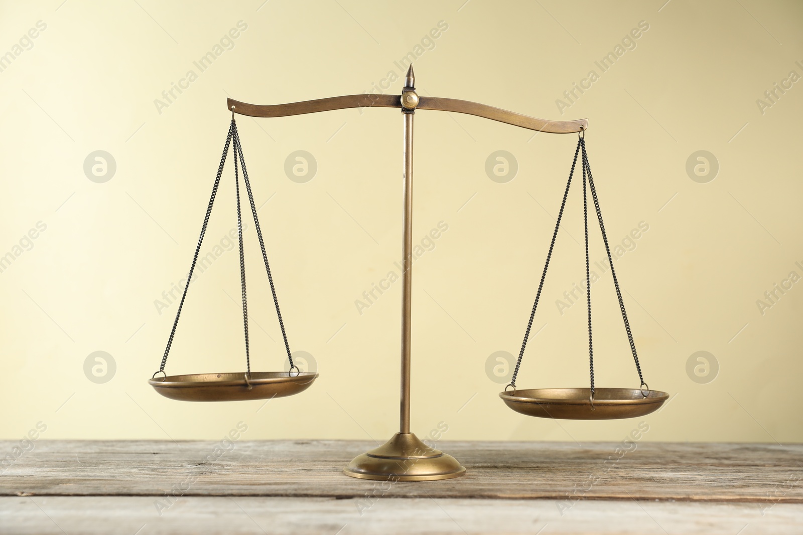 Photo of Golden scales of justice on wooden table against beige background