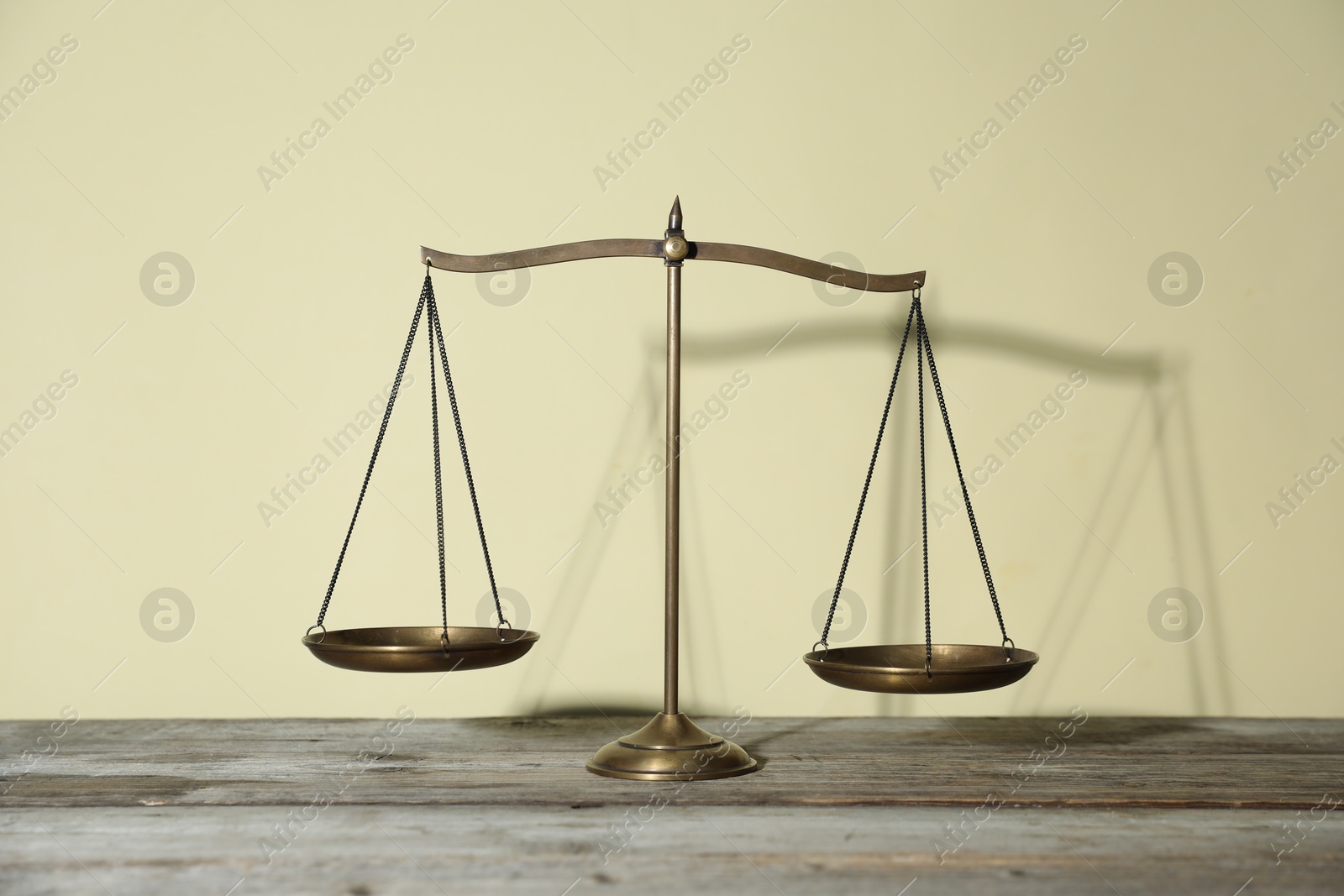 Photo of Golden scales of justice on wooden table against beige background