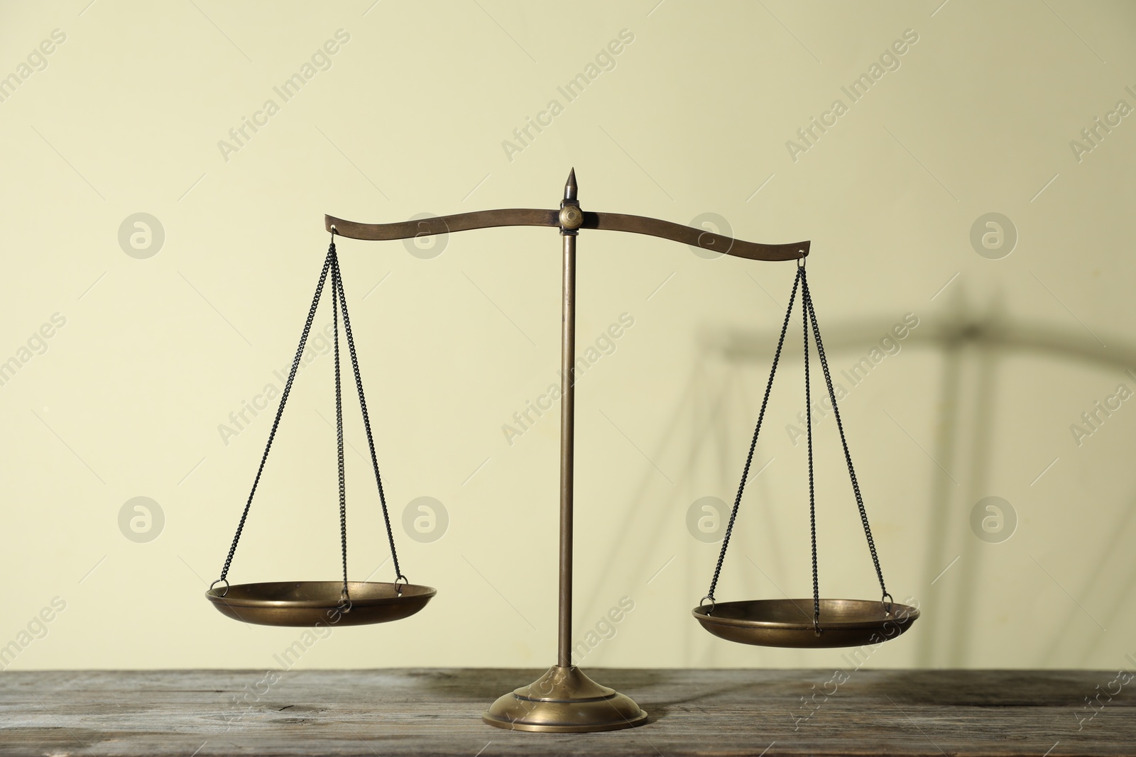 Golden scales of justice on wooden table against beige background Photo of Golden scales of justice on wooden table against beige background