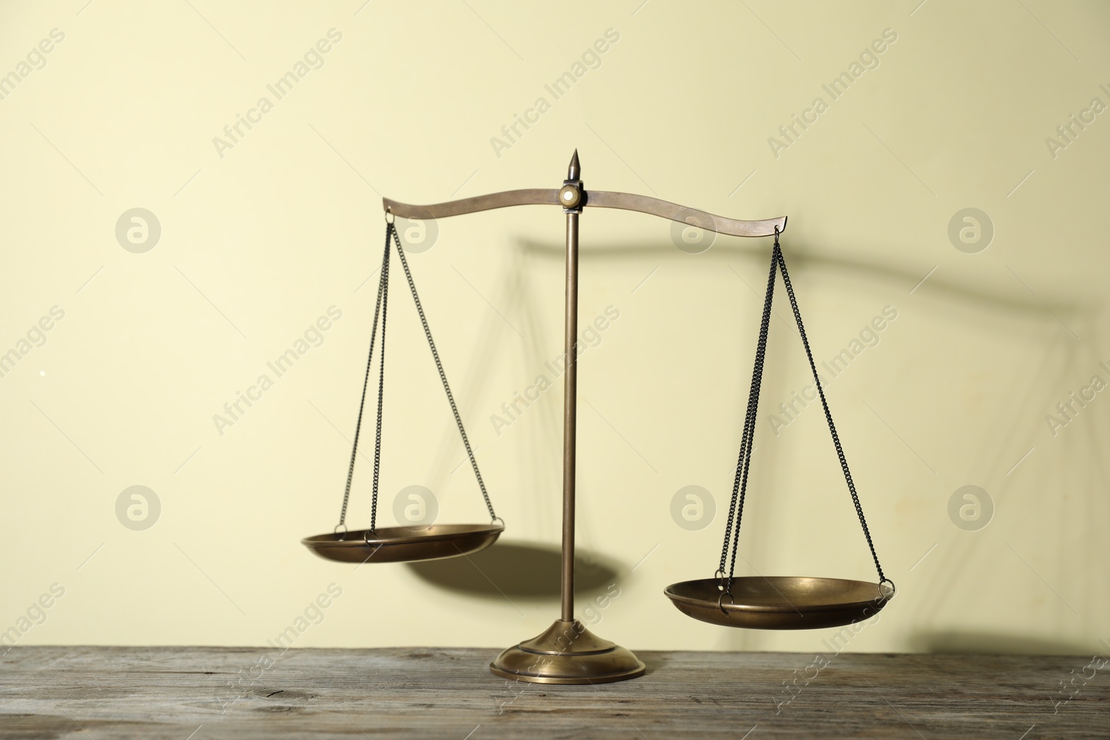 Golden scales of justice on wooden table against beige background Photo of Golden scales of justice on wooden table against beige background