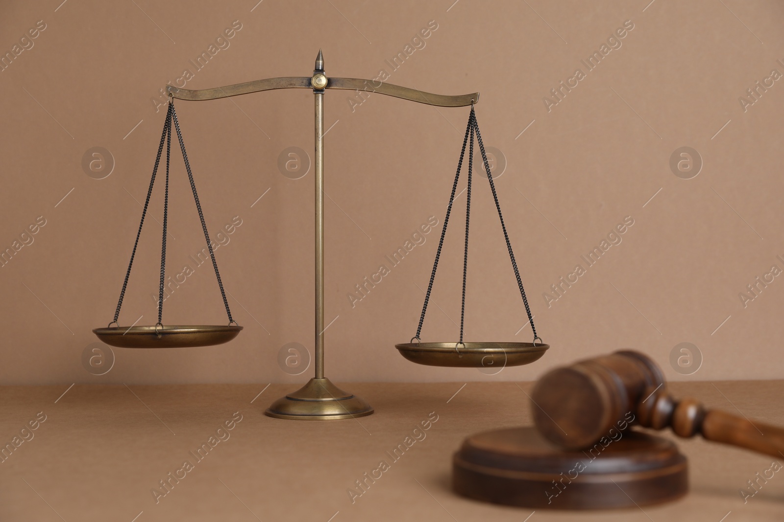 Golden scales of justice and gavel on light brown background, selective focus Photo of Golden scales of justice and gavel on light brown background, selective focus