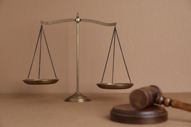 Photo of Golden scales of justice and gavel on light brown background, selective focus
