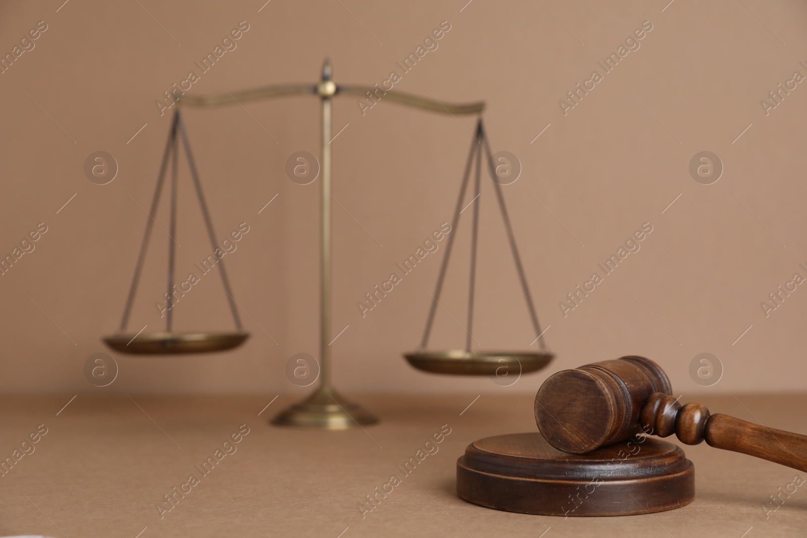 Golden scales of justice and gavel on light brown background, selective focus Photo of Golden scales of justice and gavel on light brown background, selective focus